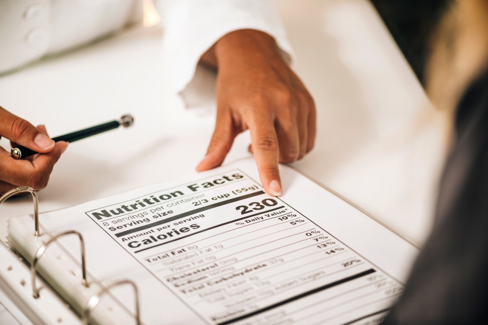 Nutritionist Explaining Nutrition Facts Label To A Client, Close-Up