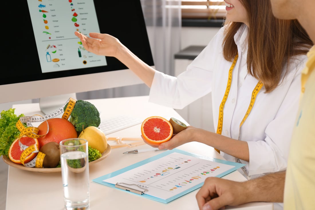 Young Nutritionist Consulting Patient at Table in Clinic, Closeu